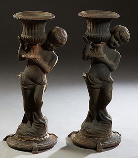 Pair of Cast Iron Figural Garden Planters, 20th c., each with a putto holding a campana form urn on his shoulder, on a stepped circular base with trip