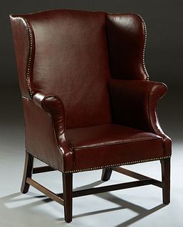 Chippendale Style Leather Wing Chair, 20th c., the arched high back over wide "wings" above rolled arms and a cushioned seat, on square tapered reeded