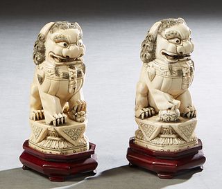 Pair of Chinese Carved Bone Foo Lion Figures, early 20th c., with scrimshaw decoration, on integral octagonal plinths, signed on the underside, on car
