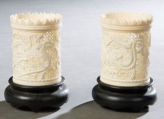 Pair of Chinese Carved Bone Toothpick Holders, early 20th c., with sawtooth rims over pierced relief dragon carved sides, on custom ebonized circular 
