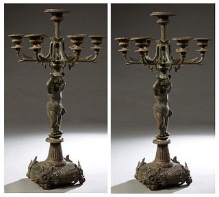 Pair of Cast Iron Figural Five Light Candelabra, 20th c., with a central straight candle cup flanked by five curved candle arms, on a putto support on
