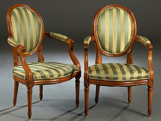 Pair of French Louis XVI Style Carved Cherry Fauteuils, 19th c., the oval medallion backs to upholstered arms, over bowed seats, on fluted tapered leg