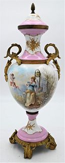 Sevres French Porcelain Urn, having pink ground with painted scene depicting girl at a well, bronze mounted handles on bronze base, height 20 inches.