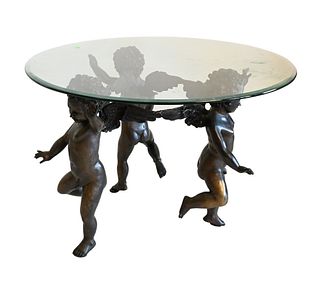 Bronze Triple Cherub Table, having glass top, height 24 inches, diameter 36 inches.