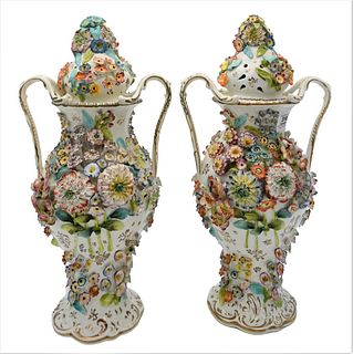 Pair of Porcelain Covered Urns, having molded flowers on body and covers, height 17 inches.