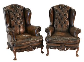 Pair of Leather Upholstered Wing Chairs, having carved bases set on hairy paw feet, height 47 inches, width 35 inches.