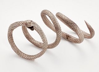 A SERPENT BANGLE, the coiled body formed of woven white metal, to a foliate