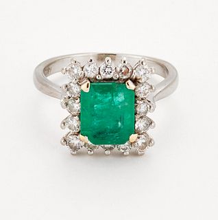 AN EMERALD AND DIAMOND CLUSTER RING, an octagonal-cut emerald in a claw set