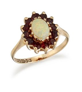 A 9 CARAT GOLD OPAL AND GARNET CLUSTER RING, an oval opal within a border o