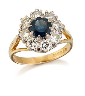 AN 18 CARAT GOLD SAPPHIRE AND DIAMOND CLUSTER RING, a round-cut sapphire in