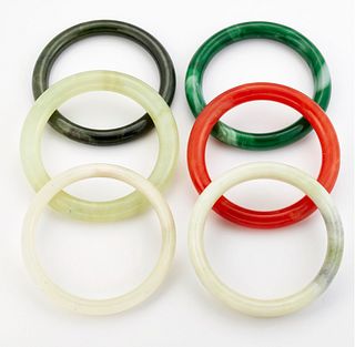 A GROUP OF FIVE JADE AND OTHER HARDSTONE BANGLES, AND A GREEN GLASS BANGLE.