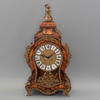 Reloj de mesa. SXX. Estilo Luis XV. Elaborado en madera enchapada y marqueteada con aplicaciones de metal dorado. Mecanismo de cuerda.