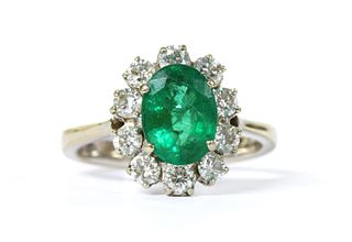 An 18ct white gold emerald and diamond oval cluster ring,