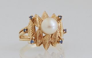 Lady's 14K Yellow Gold Dinner Ring, with a central 7mm white cultured pearl, atop relief leaves mounted with six tiny round blue sapphires, on a tripl