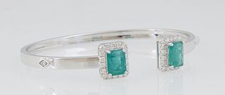 18K White Gold Bangle Bracelet, each end with a 1.6 ct. emerald atop a border of round diamonds, flanked on each side by a single surface mounted roun