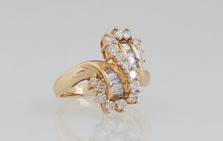 Lady's 14K Yellow Gold Bypass Dinner Ring, with a central swirled "S" mounted with eighteen round diamonds, separated by horizontal bands of baguette 
