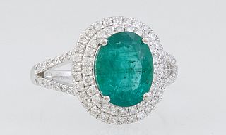Lady's Platinum Dinner Ring, with an oval 2.5 ct. emerald, atop a conforming border of round diamonds, the split shoulders of the band also mounted wi