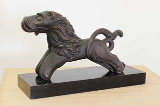 A carved wooden figure of a lion passant,