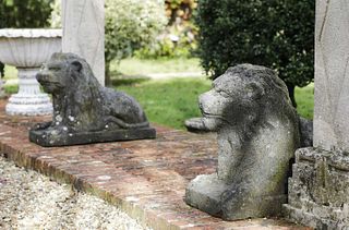 A pair of cast stone recumbent lions,