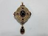 A gold and garnet Holbeinesque pendant / brooch, of oval tiered form, set to the cardinal points wit
