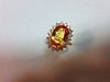 A topaz and diamond cluster ring, the oval mixed cut golden topaz claw set to a border of eighteen r