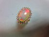 An opal and diamond cluster ring, the 17mm long oval cabochon opal, displaying good predominantly re