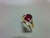 A ruby and diamond three stone ring, the emerald cut ruby four claw set between two trilliant cut di