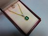 An emerald and diamond pendant set in 18ct gold, with chain, the emerald cut emerald collet set and