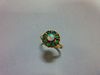 An opal and emerald cluster ring, with a round cabochon opal centre in a border of eight round cut e