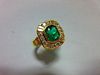 An Austrian 18ct gold emerald and diamond ring, the emerald cut emerald collet set in a border with