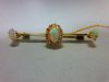 An opal and diamond bar brooch, the knife edge bar set to the centre with an oval cabochon opal in a