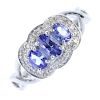 A 9ct gold tanzanite and diamond dress ring. The graduated oval-shape tanzanite line, within a singl