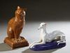 Two Italian Glazed Terracotta Figures, 20th c., of a greyhound on a blue cushion; and a seated brown cat on a cushion, Dog- H.- 9 3/4 in., W.- 15 1/4 