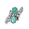 An emerald and diamond crossover ring. The oval-shape emeralds, to the brilliant-cut diamond crossov