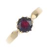 An early 20th century 18ct gold garnet single-stone ring. The circular-shape garnet, to the tapered