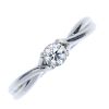 A platinum diamond single-stone ring. The brilliant-cut diamond, to the crossover shoulders and slig