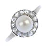 An early 20th century platinum cultured pearl and diamond cluster ring. The cultured pearl, measurin