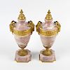 A pair of ormolu-mounted pink marble urns. Each of neoclassical form with cast domed finial over a p