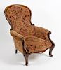 A mid 19th century mahogany-framed spoon-back easy chair. The deep-buttoned spoon back, scroll arms