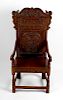 An early 20th century carved oak Wainscot-style chair. The foliate scrolling crest above carved back