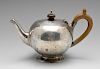 A late Victorian silver teapot of globular form having scroll capped wooden handle raised upon foote