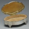 An early twentieth century silver mounted trinket box of shaped oval outline and raised on four spla