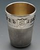 A cased Victorian silver novelty shot cup modelled as a thimble, with raised lettering 'Just a thimb