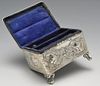 An Edwardian silver mounted jewellery box of oblong form, embossed with putti and opening to a compa