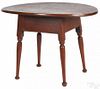 Painted pine tavern table with an oval top and a red surface, 25'' h., 35 1/2'' w.