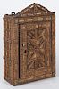 Tramp art carved hanging cabinet, 20th c., with an open carving, backed with fabric panels
