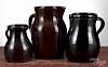 Three stoneware pitchers, 19th c., with Albany slip glaze, 12 1/4'' h., 11'' h., and 8 1/4'' h.