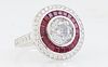 Lady's 18K White Gold Dinner Ring, with a central round 2.5 carat diamond within a border of princess cut rubies and an outer border of round diamonds