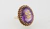 18K Yellow Gold Dinner Ring, with an approx. 20 carat oval amethyst, with a gilt incised flower decoration on top, mounted with two diamond chips, abo