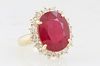 Lady's 14K Yellow Gold Dinner Ring, with an oval 10.86 carat oval ruby atop a border of round diamonds, total diamond wt.- 1.29 cts., Size 6 1/2, with